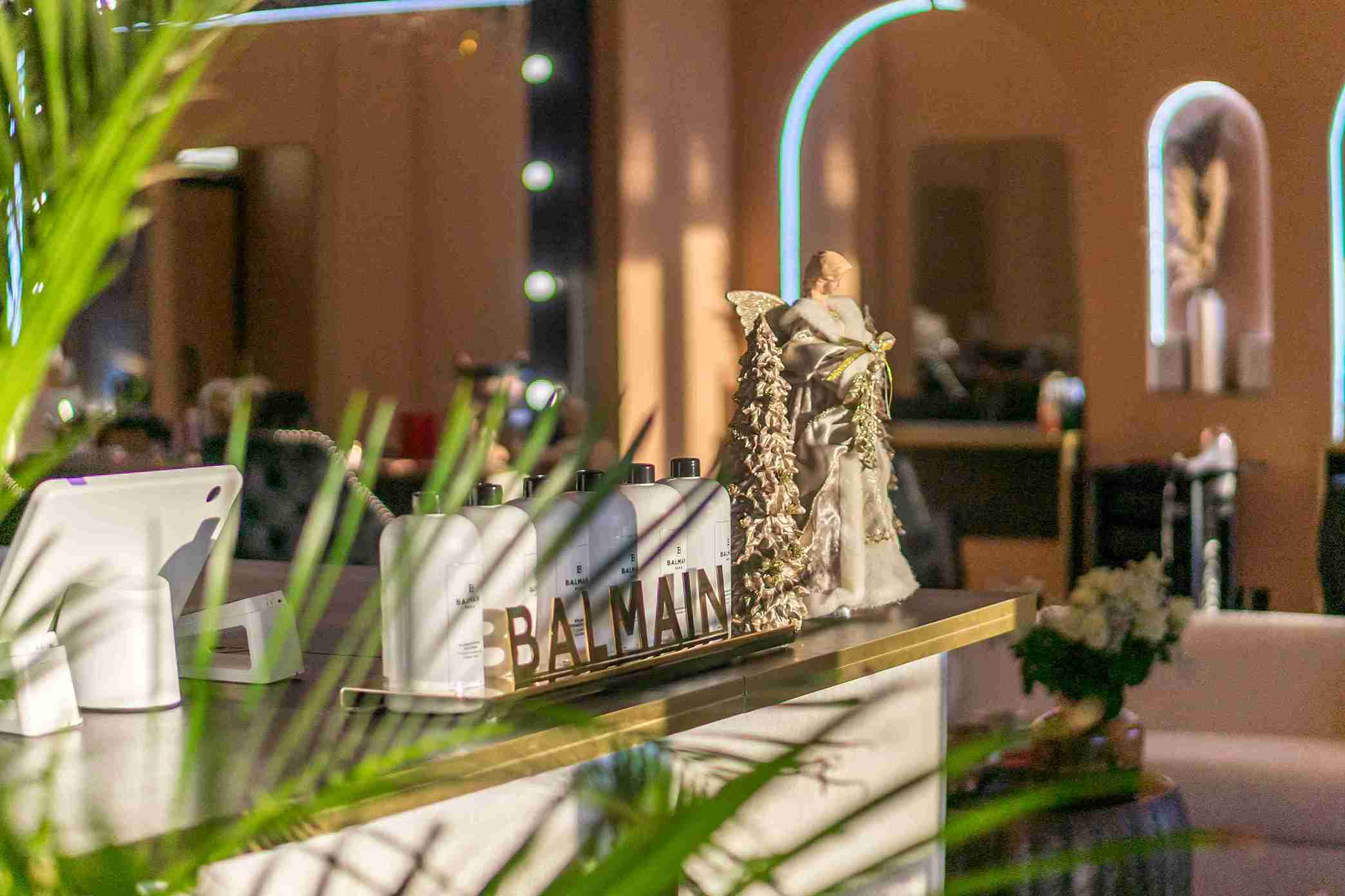 Close-up of the stylish reception bar showcasing Balmain and Kérastase professional hair products and holiday decor.
